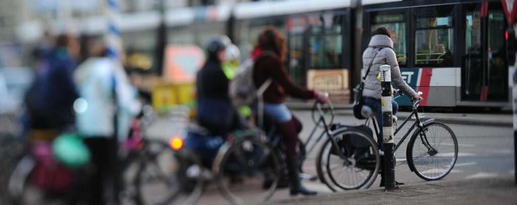 Personas montadas en bicicleta esperan el paso de un autobus